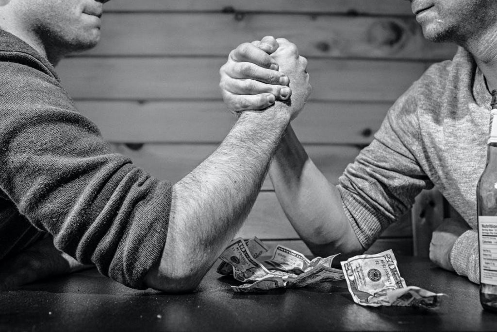 Two men betting over an arm wrestle 