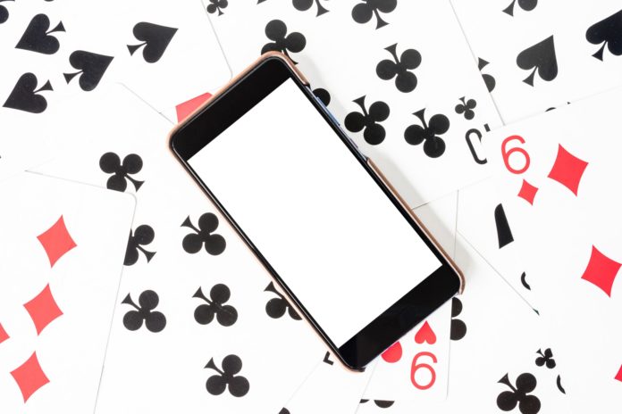 Smart phone with white screen on playing cards background.