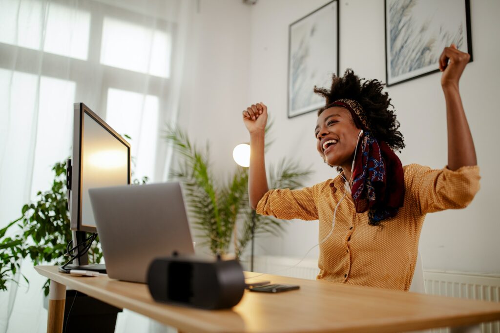 Image of nice woman wearing casual clothes using headphones and dancing while sitting in office.