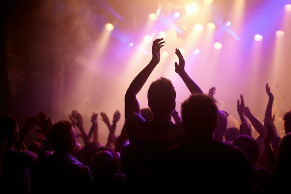 Rock on. Rear view of a music fan dancing with her arms raised at a music concert.