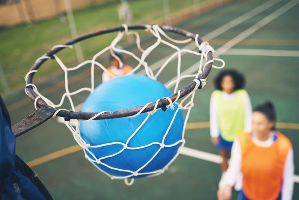 Ball in net, netball and sports outdoor with team, fitness and active lifestyle with athlete on cou