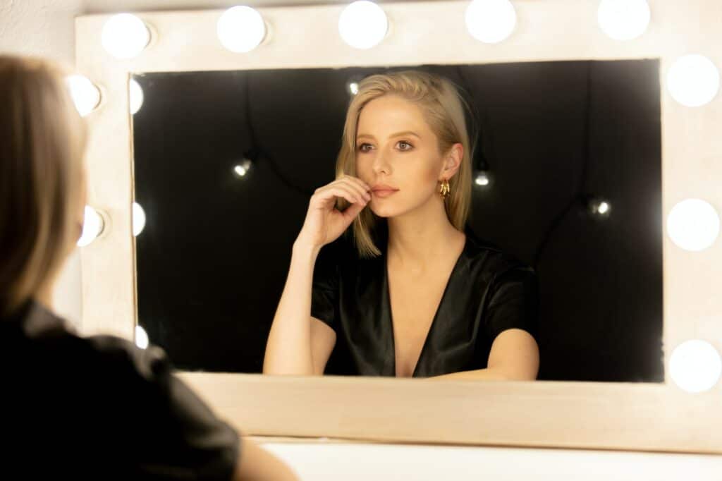 Beautiful blonde woman near makeup mirror
