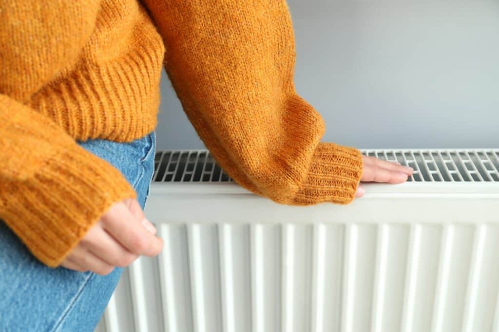 Concept of heating season with girl sitting on radiator