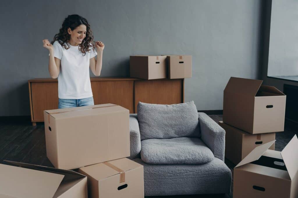 Excited young woman is packing things. Spanish girl moves to new house. Real estate purchase.