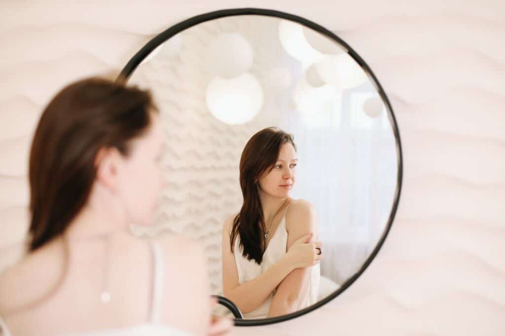Portrait of calm pretty girl. Portrait of the woman reflected in mirror in a cozy light room in the
