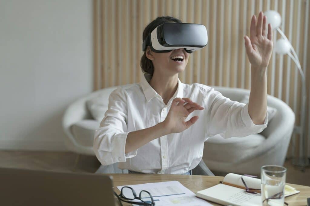 Happy woman office worker wearing vr goggles interacting with virtual reality at work