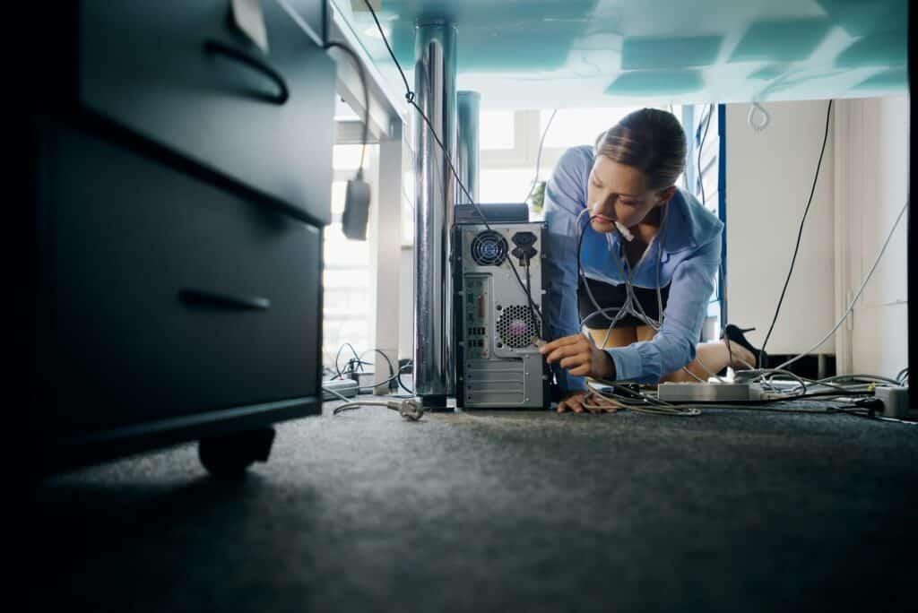 Young Secretary Connecting Cables To Pc In Office