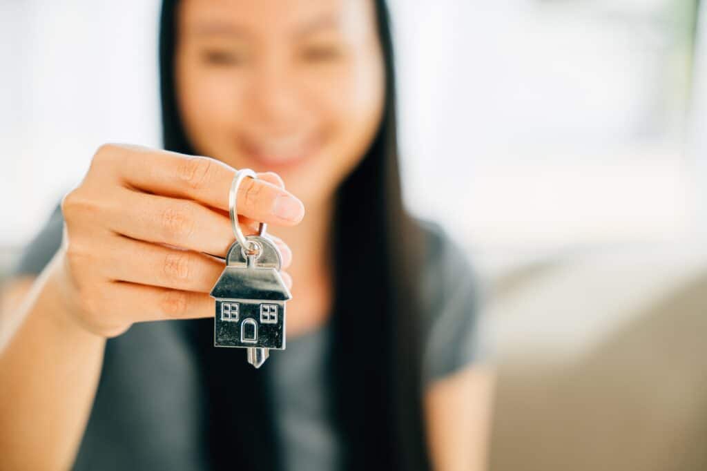 A woman's hand holds house key highlighting homeowners' achievement