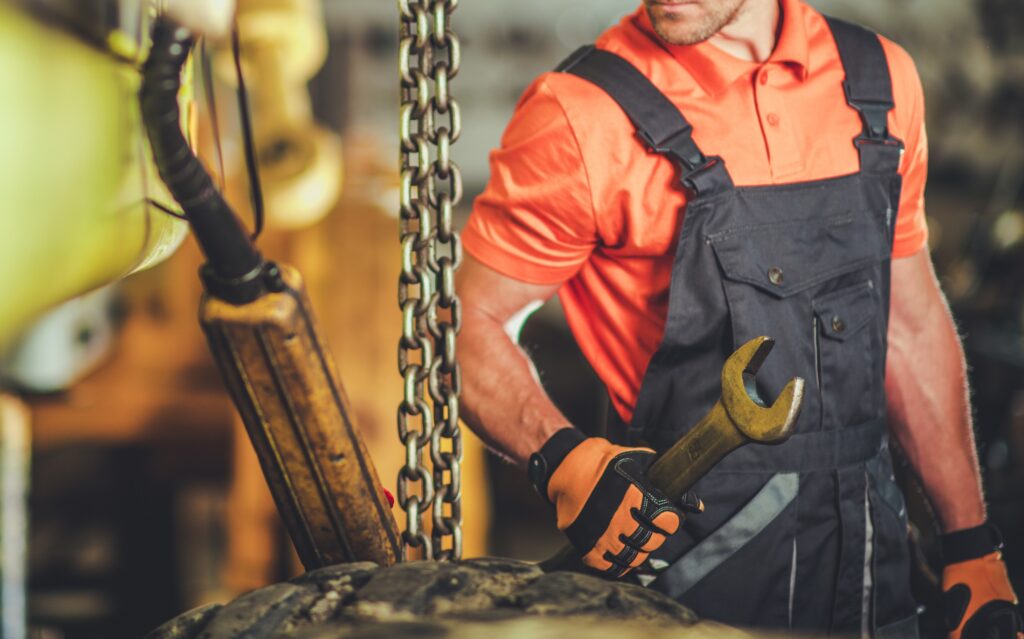 Skilled Worker Using a Wrench While Repairing Heavy Machinery in a Workshop Setting