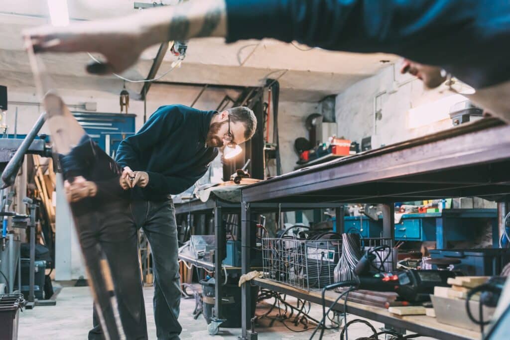 Metalworkers inspecting sheet copper in forge workshop